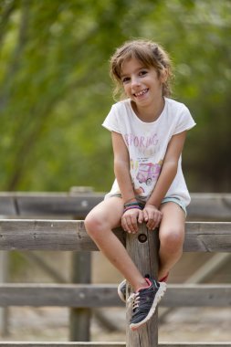 Bir Mountain Park birkaç gövdeleri üzerinde oturan kız. 