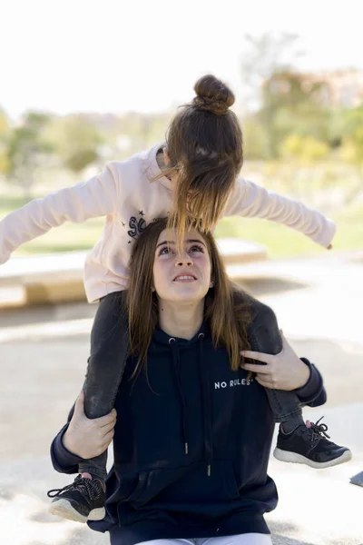 Lány mászni a vállán a húga. — Stock Fotó