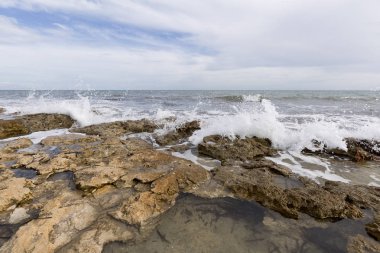 Santa Pola dalgalarda ile kayalık plaj.