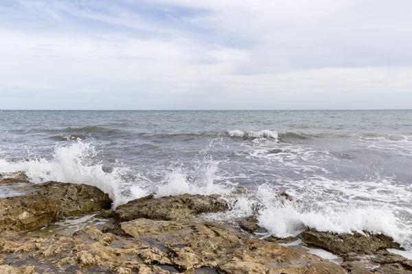 Skalnatá pláž s vlnami v Santa Pola. — Stock fotografie