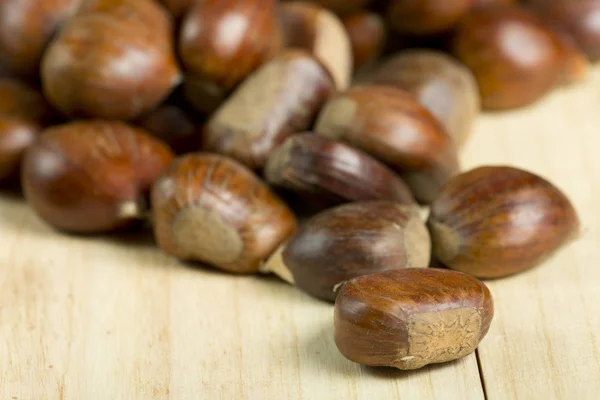 Kastanjes op grenen houten achtergrond. — Stockfoto