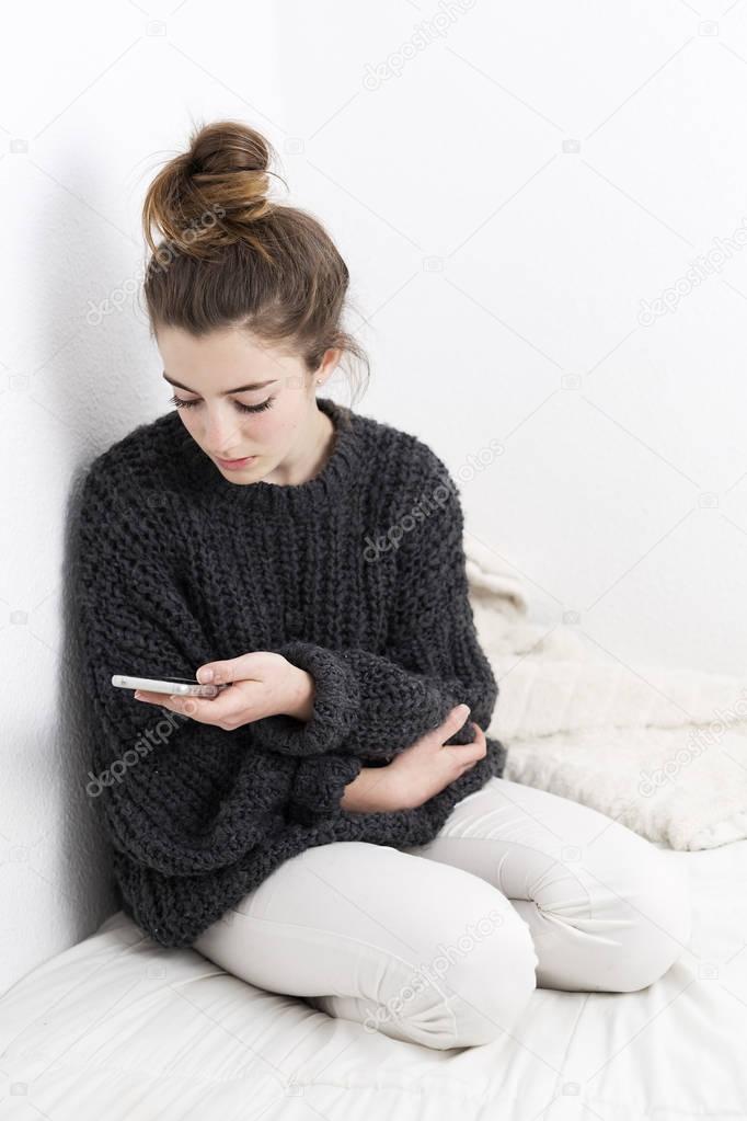 Young woman looking at the mobile phone on a white background. 