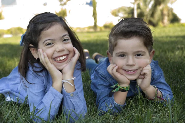 Couple of brothers lying on the lawn of a park. — Stock Photo, Image