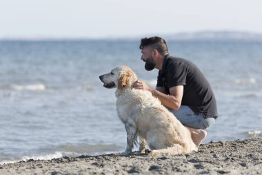 Adam bir plajda köpeğiyle.