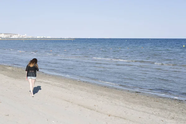 Mujer joven caminando descarte por una playa — Foto de Stock