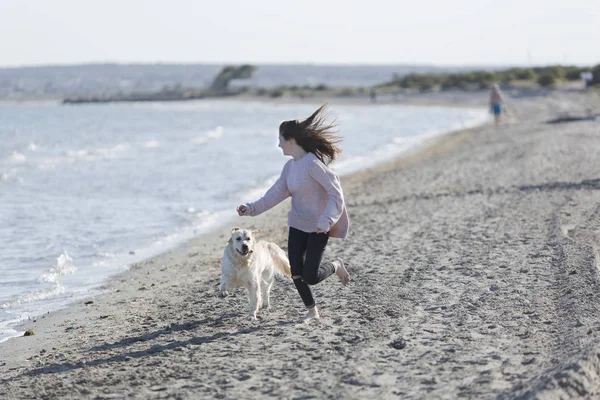 Adolescente jugando con su perro en una playa . — Foto de Stock