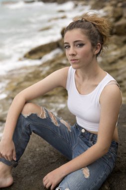 kayaların üzerinde oturan genç kız.