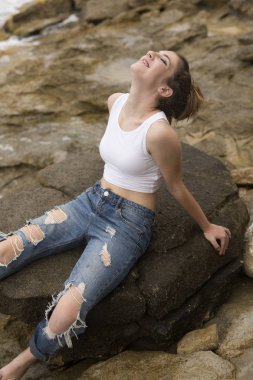 kayaların üzerinde oturan genç kız.