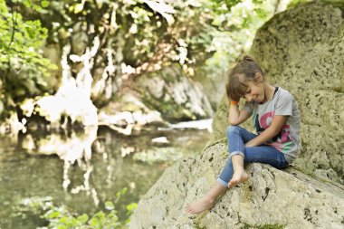Bir kaya şelale yanında oturan kız.