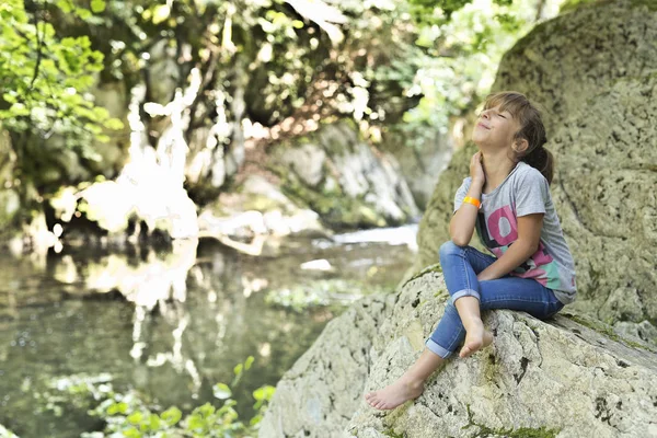 Girl sitting on a rock next to the Waterfall. — Stock Photo, Image