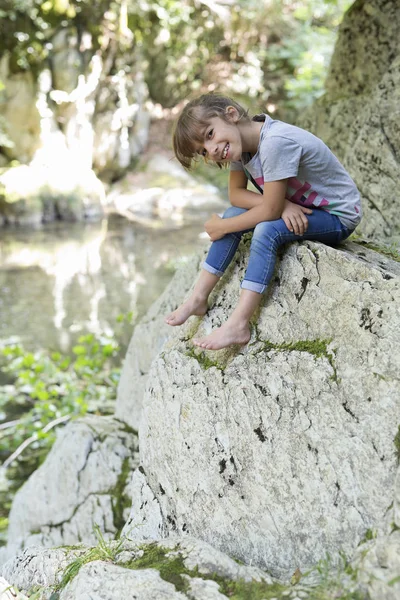 Bir kaya şelale yanında oturan kız.