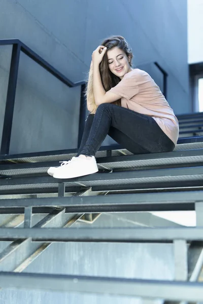 Adolescente sonriendo sentada en una escalera de metal — Foto de Stock