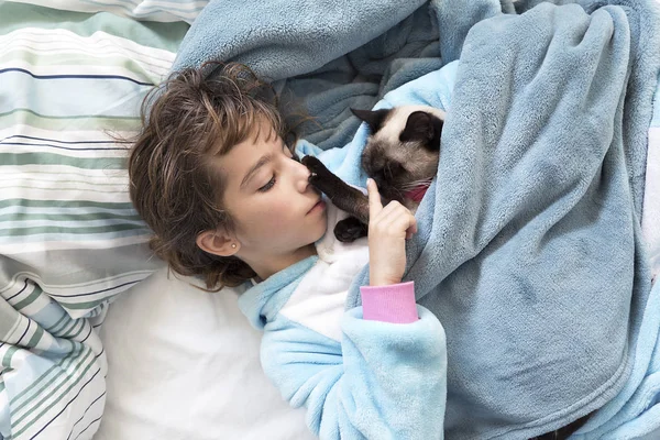 Маленька дівчинка лежить на ліжку зі своєю кішкою — стокове фото