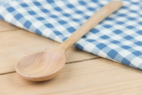 Closeup wooden spoon on napkin blue and white plaid on wooden table — Stock Photo, Image