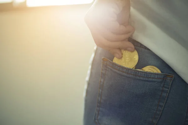 Woman drop bitcoin to pocket, close-up, electronic finance