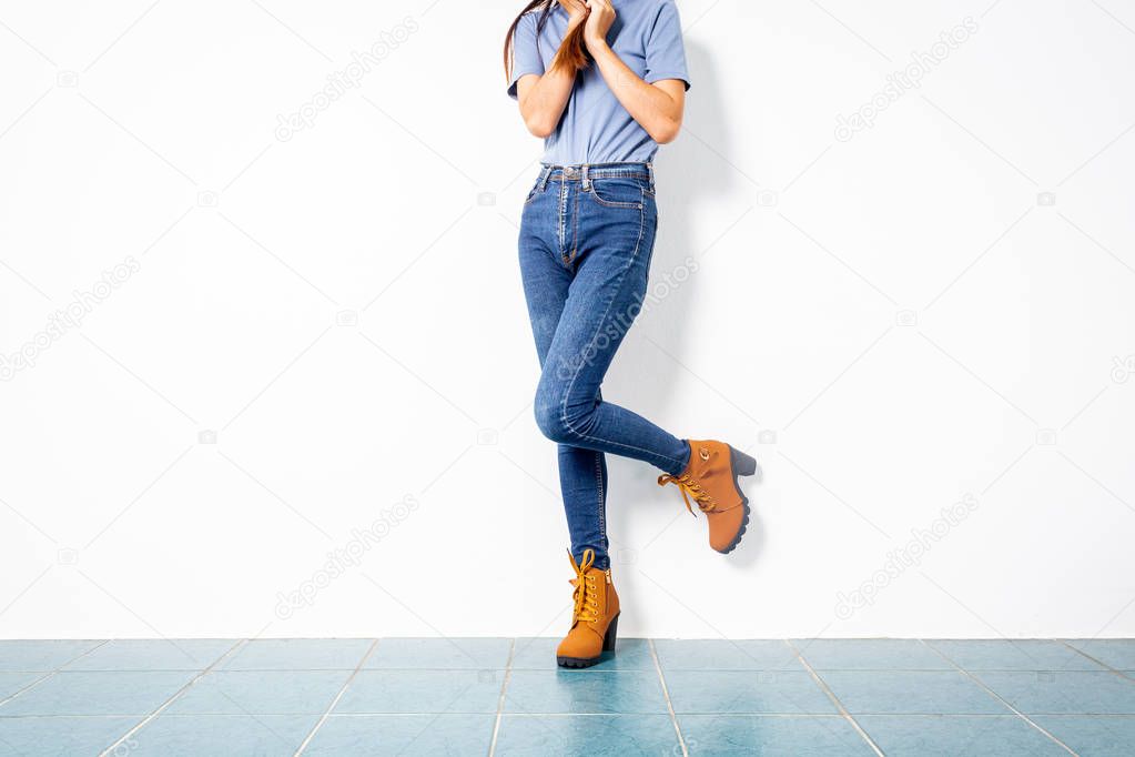 Young girl blue jeans brown shoes wall white.