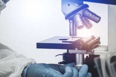 Koronavirüs kovid 19 yapan erkek bilim adamı aşı araştırmaları için biyoloji laboratuarında koruma giysisi kullanıyor..