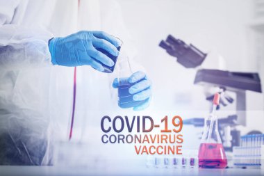 COVID-19 VACCINE metni: Koronavirüs covid-19 yapan erkek bilim adamı, biyoloji laboratuvarında aşı araştırmaları için giysi ile korunuyor.