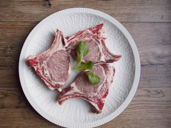 Ahşap arka plan üzerinde beyaz bir tabak içinde İber domuz pirzolası