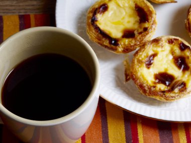 Bir tabak ve bir fincan siyah kahve kremalı tart