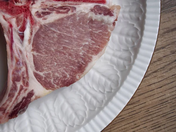 Ahşap arka plan üzerinde beyaz bir tabak içinde İber domuz pirzolası