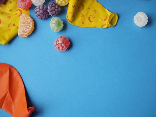 Globos y caramelos desinflados de colores sobre fondo azul — Foto de Stock