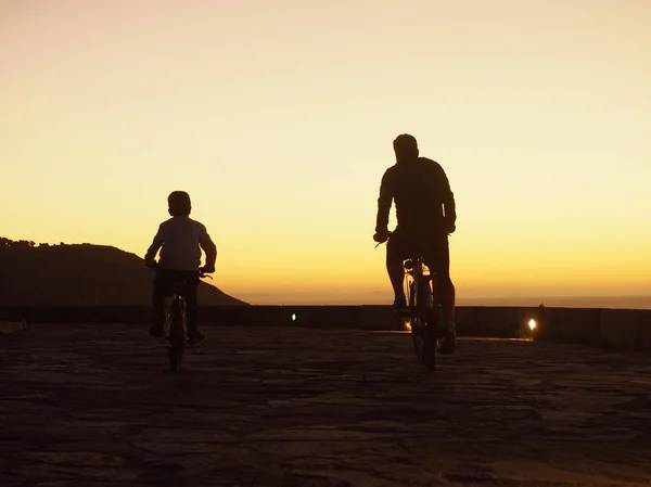 Father and son ridding bicycle in the sunset — Stock Photo, Image