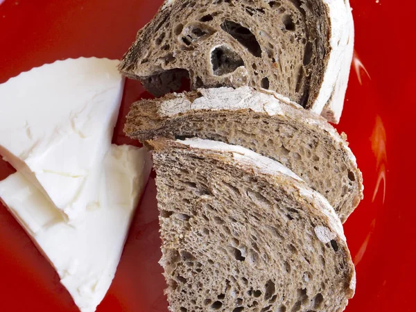 Солодовый ржаной хлеб с сыром на красной тарелке — стоковое фото