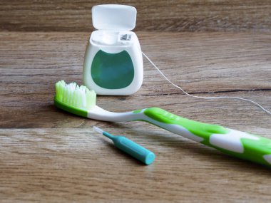 Diş ipi, diş fırçası ve interdental fırça ahşap arka plan üzerinde
