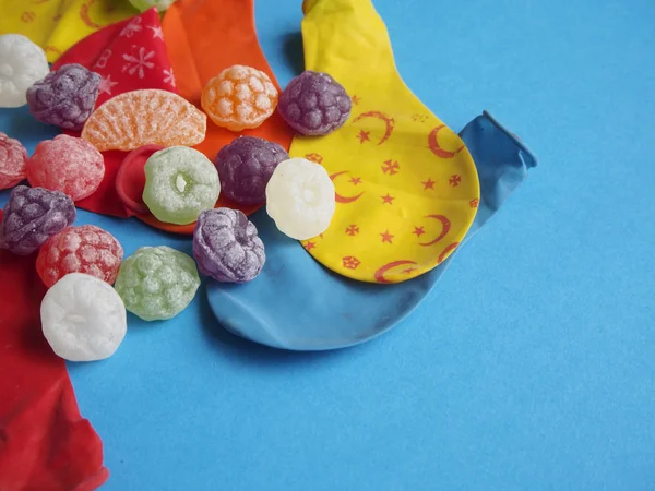 Globos y caramelos desinflados de colores sobre fondo azul — Foto de Stock