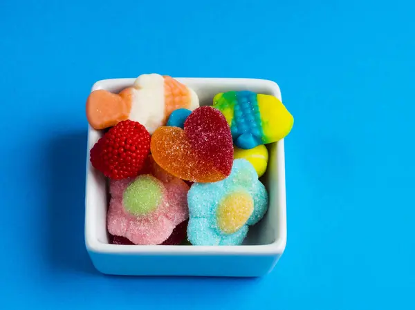 Caramelos de gelatina en un bol sobre fondo azul — Foto de Stock