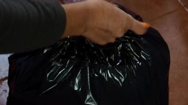 Eller çöp torbasını kapatıyor.