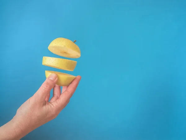 Hand Met Gouden Appel Gesneden Blauwe Achtergrond Met Kopieerruimte — Stockfoto