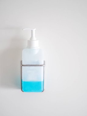 Beyaz duvarda bir şişe el dezenfektanı var.