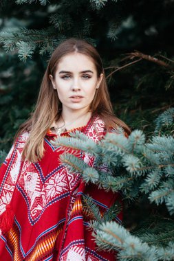 Güzel genç kızı ormanda açık havada kırmızı panço