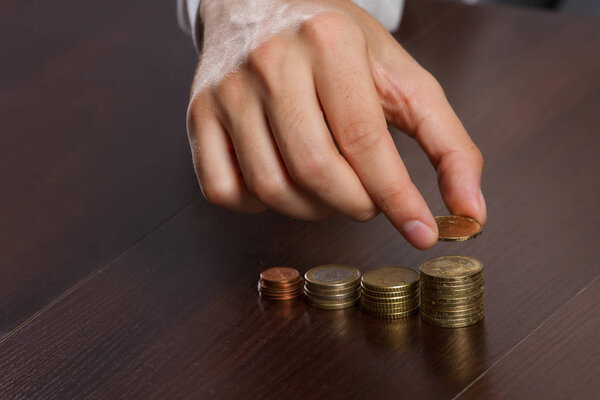 young businessman hand holding a coin with row stacks