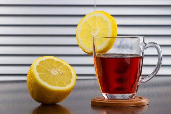 Copa de vidrio de té caliente y un limón — Foto de Stock