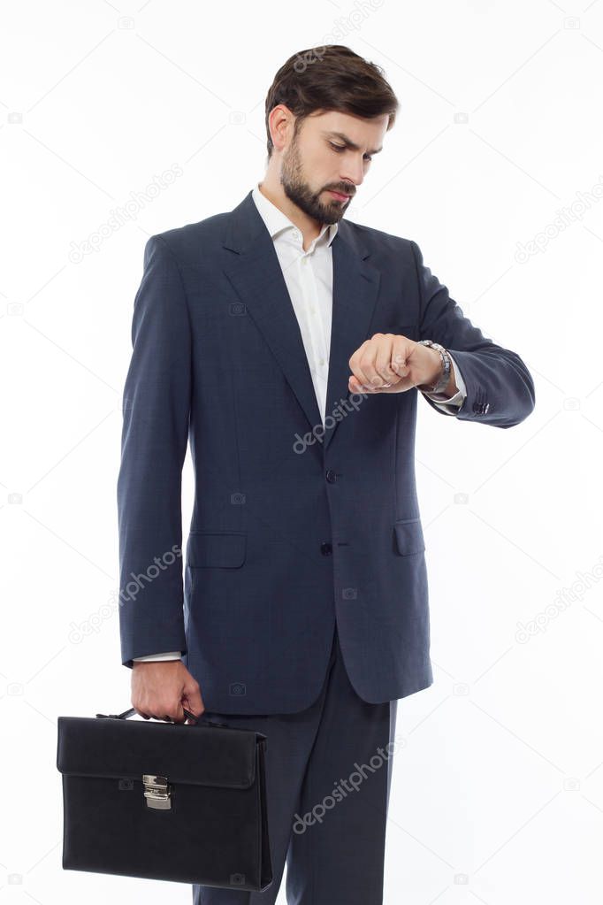Attractive businessman with suitcase looks at the clock