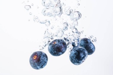 Bir organik yabanmersini, hava kabarcıkları ve beyaz arka planla suya batıyor. Makro detaylı yakın çekim.