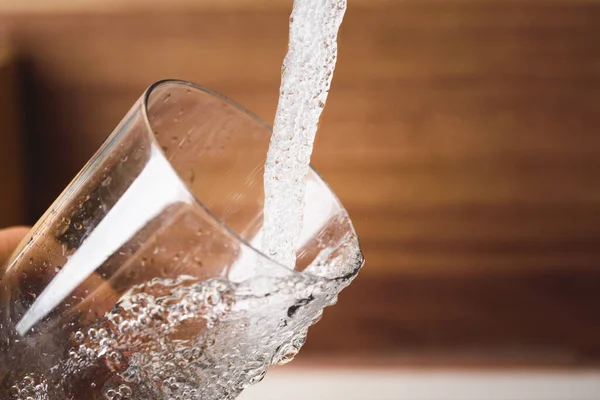 Het vullen van glas water uit roestvrij stalen keukenkraan. Drinkwaterconcept — Stockfoto