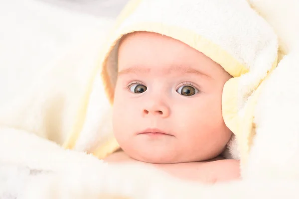 Entzückende 6 Monate alte Säugling auf einem Bett auf dem Bauch mit dem Kopf nach oben in die Kamera blickend mit ihren großen Augen. natürliches Licht. — Stockfoto