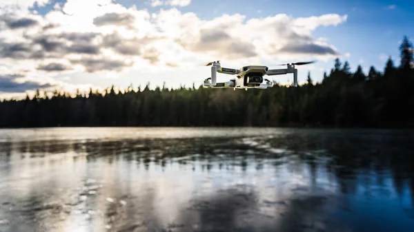 Graz, Áustria - 29 de dezembro de 2019. DJI Mavic Mini drone voando no campo acima do lago congelado no dia ensolarado de inverno — Fotografia de Stock