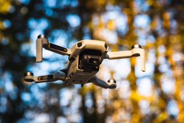 Graz, Austria: 02.01.2020 - Close up shoot of a DJI Quadcopter Drone Mavic mini 249g. Drone flying in sunny forest. clipart