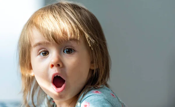 Förtjusande baby med roligt uttryck inomhus. Porträtt av 1- 2 årig flicka i kroppen ser mycket rädd. — Stockfoto