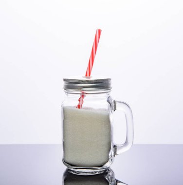 Drink glass jar with red straw full of sugar. Isolated on white background.