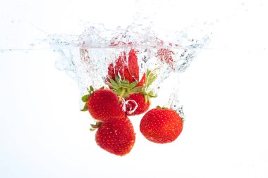 Strawberries falling into water causing bubbles all around it. Healthy food concept. Underwater, splash photography. clipart