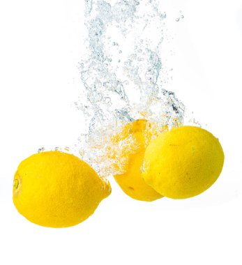 Limonlar suya düşer ve beyaz arka planda batar. Lezzetli ve sağlıklı yemekler.