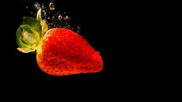 イチゴは水に落ち 周りの泡を発生させます 健康食品の概念 黒の背景 — ストック写真