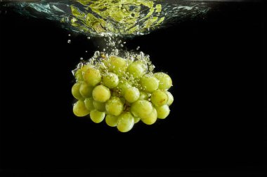 Taze yeşil üzüm demet suya sıçraması. Siyah arka planda yalıtılmış
