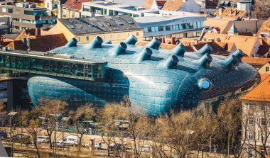 Graz, Avusturya - 10.03.2020: Graz Avusturya 'daki Kunsthaus sanat müzesinin tepesi, etrafındaki terra cotta çatılarının aksine yer alıyor